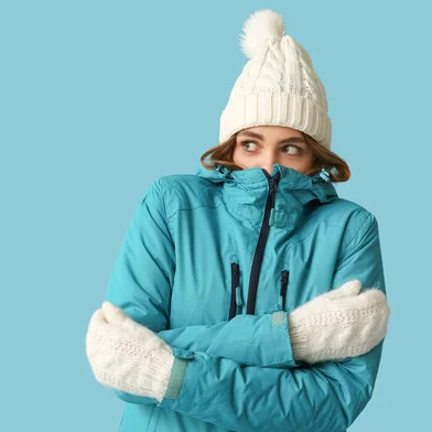 Frozen young woman in warm winter clothes on blue backgroundIndexador: Leonid IastremskyiFonte: 690413846<!-- NICAID(15786606) -->
