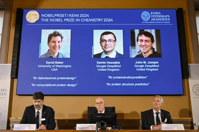 (Bottom L-R) Chair of the Nobel Prize Committee for Chemistry Heiner Linke, Secretary General of the Royal Swedish Academy of Sciences Hans Ellegren and Member of the Nobel Prize Committee for Chemistry Johan Aqvist announce the laureates of the 2024 Nobel Prize in Chemistry, (On screen L-R)  David Baker, Demis Hassabis and John M Jumper, at the Royal Swedish Academy of Sciences in Stockholm, Sweden on October 9, 2024. The Royal Swedish Academy of Sciences has decided to award the 2024 NobelPrize in Chemistry with one half to David Baker for computational protein design and the other half jointly to Demis Hassabis and John M. Jumper for protein structure prediction. (Photo by Jonathan NACKSTRAND / AFP)Editoria: HUMLocal: StockholmIndexador: JONATHAN NACKSTRANDSecao: chemistryFonte: AFPFotógrafo: STR<!-- NICAID(15886635) -->