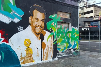 Leandro Rodrigues / Agência RBS Assim como no ano passado, a Cidade Baixa, bairro boêmio de Porto Alegre, ganhou em uma de suas esquinas uma homenagem a um brasileiro premiado no Globo de Ouro.Se em 2025 foi Fernanda Torres, agora é Wagner Moura quem aparece sorridente com a estatueta de Melhor Ator em Filme de Drama, troféu conquistado no domingo passado por O Agente Secreto.<!-- NICAID(16203754) -->