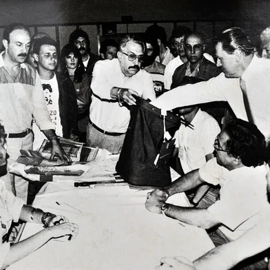 CAXIAS DO SUL, RS, BRASIL, 16/11/1986 - FOTO DE ARQUIVO - Apuração de votos na eleição para governador em 1986, no Salão dos Capuchinhos, em Caxias do Sul. À direita, o juiz eleitoral Pedro Panazzolo (com a mão na urna), Milton Rossarolla (segurando a urna), Victorio Trez (à direita) e José Tessari (de óculos, mais atrás).  Pedro Simon foi eleito. (Roberto Scola/Pioneiro)<!-- NICAID(13164790) -->