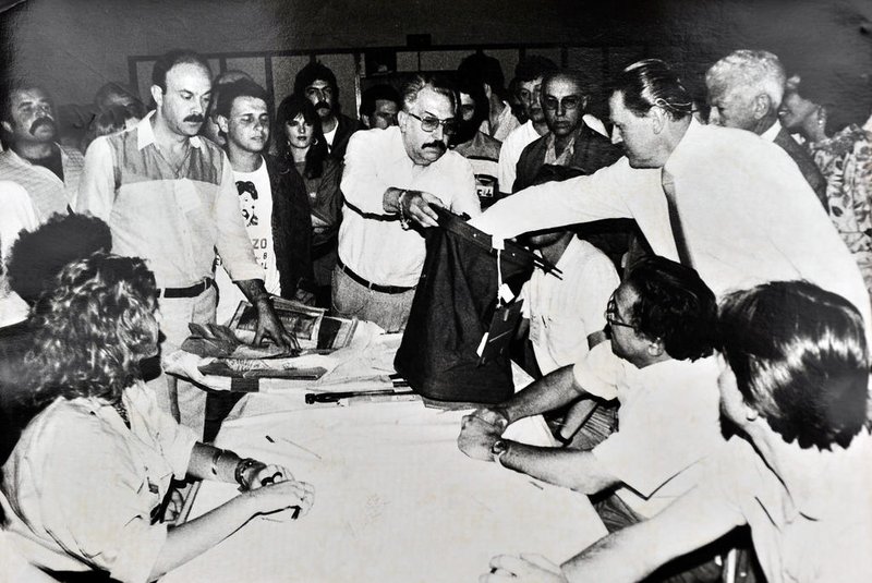 CAXIAS DO SUL, RS, BRASIL, 16/11/1986 - FOTO DE ARQUIVO - Apuração de votos na eleição para governador em 1986, no Salão dos Capuchinhos, em Caxias do Sul. À direita, o juiz eleitoral Pedro Panazzolo (com a mão na urna), Milton Rossarolla (segurando a urna), Victorio Trez (à direita) e José Tessari (de óculos, mais atrás).  Pedro Simon foi eleito. (Roberto Scola/Pioneiro)<!-- NICAID(13164790) -->