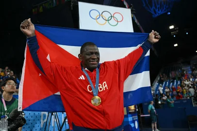 Gold medallist Cuba's Mijain Lopez Nunez poses with the Cuban flag and his medal after the presentation ceremony for the men's greco-roman 130kg wrestling event at the Champ-de-Mars Arena during the Paris 2024 Olympic Games, in Paris on August 6, 2024. (Photo by Luis ROBAYO / AFP)<!-- NICAID(15834446) -->