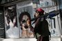 A Taliban fighter walks past a beauty salon with images of women defaced using spray paint in Shar-e-Naw in Kabul on August 18, 2021. (Photo by Wakil KOHSAR / AFP)<!-- NICAID(14866163) -->