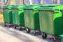 Large green plastic trash cans on city street. Containers on wheels with a handle to collect commercial and resident trash. Disposal of household and industrial waste. Place for text.Contêiner de lixo. Foto: vita / stock.adobe.comFonte: 422785748<!-- NICAID(15473928) -->