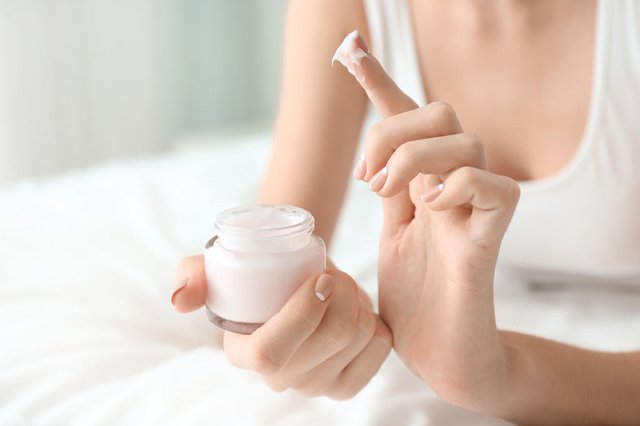 Young woman with jar of hand cream at home, closeupFonte: 198666067<!-- NICAID(14325169) -->