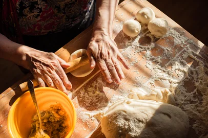 Senior woman hands rolling out dough in flour with rolling pin in her home kitchenFonte: 88943992<!-- NICAID(16047006) -->