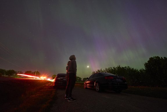 People stop along a country road near London, Ontario to watch the Northern lights or aurora borealis during a geomagnetic storm on May 10, 2024. The most powerful solar storm in more than two decades struck Earth on May10, 2024, triggering spectacular celestial light shows in skies from Tasmania to Britain -- and threatening possible disruptions to satellites and power grids as it persists into the weekend. Auroras are often observed in Canada's northern regions, but rarely in southern Ontario. (Photo by Geoff Robins / AFP)<!-- NICAID(15761504) -->