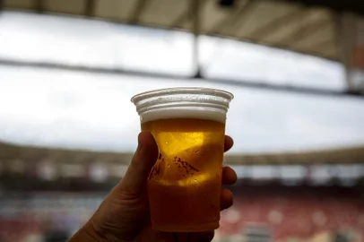 Disposable glass with beer. Soccer stadium on the background*A PEDIDO DE DANIEL ANGELI* Disposable glass with beer. Soccer stadium on the background. - Foto: 9parusnikov/stock.adobe.comIndexador: Piotr PiatrouskiFonte: 331686098<!-- NICAID(15212985) -->