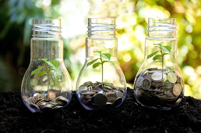 Money saving economy environment.Â  Plants growing in money coins in glass jar for investment planning travel and retirement. Nature Background.Â  Saving and Investment Concept<!-- NICAID(16172087) -->