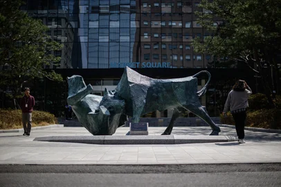 People walk past a bull and bear sculpture in front of the Korea Exchange building in Seoul on April 7, 2025. Asian equities collapsed on a black Monday on April 7 for markets after China hammered the United States with its own hefty tariffs, ramping up a trade war many fear could spark a recession. (Photo by ANTHONY WALLACE / AFP)<!-- NICAID(16011956) -->