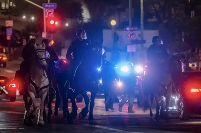 Mounted Los Angeles Police Department (LAPD) officers ride their horses close to the Federal Building in downtown after a curfew was put into effect following days of protests in response to federal immigration operations in Los Angeles on June 10, 2025. Los Angeles police began arresting people in the city's downtown late on June 10, as groups gathered in violation of an overnight curfew after a fifth day of protests against Donald Trump's immigration crackdown. (Photo by Apu GOMES / AFP)<!-- NICAID(16057055) -->