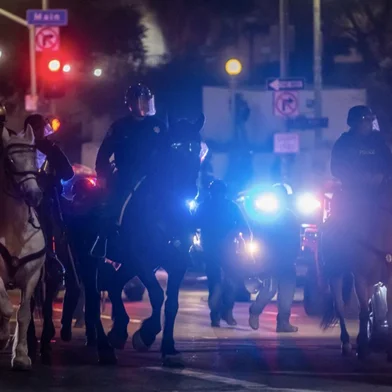 Mounted Los Angeles Police Department (LAPD) officers ride their horses close to the Federal Building in downtown after a curfew was put into effect following days of protests in response to federal immigration operations in Los Angeles on June 10, 2025. Los Angeles police began arresting people in the city's downtown late on June 10, as groups gathered in violation of an overnight curfew after a fifth day of protests against Donald Trump's immigration crackdown. (Photo by Apu GOMES / AFP)<!-- NICAID(16057055) -->