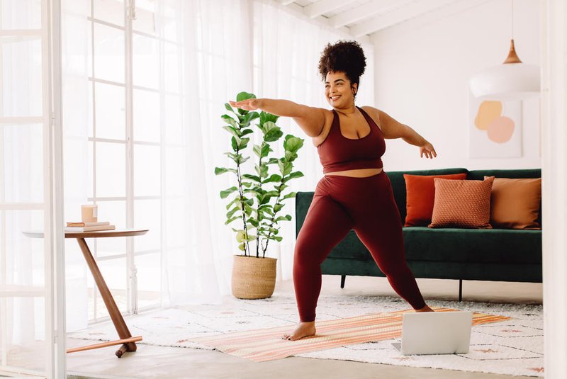 Full length of healthy woman exercising at home watching online video on laptop. Beautiful female in sports wear doing yoga.Indexador: Gabriel MaiaFonte: 442679488<!-- NICAID(15611751) -->