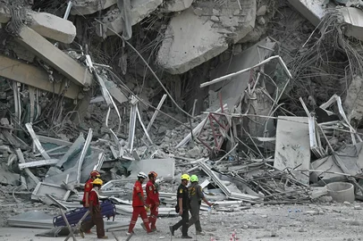 Rescue workers walk past the debris of a construction site after a building collapsed in Bangkok on March 28, 2025, following an earthquake. A powerful earthquake rocked central Myanmar on March 28, buckling roads in capital Naypyidaw, damaging buildings and forcing people to flee into the streets in neighbouring Thailand. (Photo by Lillian SUWANRUMPHA / AFP)<!-- NICAID(16005235) -->