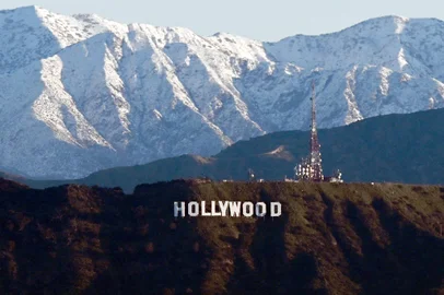 (FILES) In this file photo taken on March 02, 2023 snow capped mountains stand on the skyline behind a view of the Hollywood sign following heavy rain from winter storms, as seen from the Kenneth Hahn State Recreation Area, in Los Angeles, California. - Hollywood television and movie writers will go on strike, their union said May 1, 2023, after talks with studios and streamers on pay and other conditions ended without a deal. (Photo by Patrick T. Fallon / AFP)Editoria: ACELocal: Los AngelesIndexador: PATRICK T. FALLONSecao: cinema industryFonte: AFPFotógrafo: STF<!-- NICAID(15417481) -->