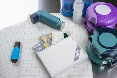 Asthma, allergie, illness relief concept, salbutamol inhalers, aerosol medication, drugs and paper on chrome background<!-- NICAID(16059347) -->