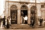 Nicola Di Leone (de branco) e seu filho Natale (de terno) em pé, na porta da sua casa de comércio Nápoli em Porto Alegre na esquina da Rua da Praia com Rua Gen. João Manoel.<!-- NICAID(14719209) -->