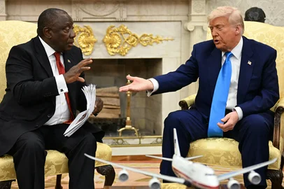 US President Donald Trump hands papers to South African President Cyril Ramaphosa during a meeting in the Oval Office of the White House in Washington, DC, on May 21, 2025. South African President Cyril Ramaphosa meets Donald Trump on Wednesday amid tensions over Washington's resettlement of white Afrikaners that the US president claims are the victims of "genocide." (Photo by Jim WATSON / AFP)Editoria: POLLocal: WashingtonIndexador: JIM WATSONSecao: diplomacyFonte: AFPFotógrafo: STF<!-- NICAID(16042557) -->
