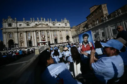 A faithful holds a portrait of late teenager Carlo Acutis in front of Saint Peter's Basilica ahead of a Holy Mass and canonisation ceremony of Blessed Carlo Acutis and Pier Giorgio Frassati in St Peter's Square at the Vatican on September 7, 2025. An Italian teenager dubbed "God's Influencer" for his efforts to spread the Catholic faith online will become the first millennial saint Sunday at a canonisation attended by thousands of pilgrims. Computer whiz Carlo Acutis, who died of leukemia in 2006 aged 15, will be raised to sainthood by Pope Leo XIV in a solemn ceremony in St Peter's Square at the Vatican. Italian Pier Giorgio Frassati, a mountaineering enthusiast who died in 1925 and was known for his social and spiritual commitment, will also be made a saint on September 7, 2025.