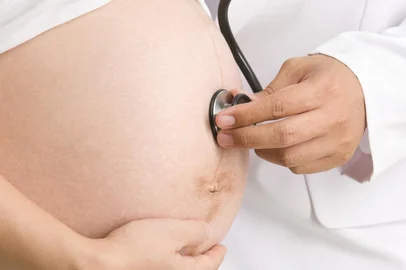 A doctor is checking the baby's health in a mother's womb. Shot against white background.Indexador: Rudyanto WijayaFonte: 9698708Fotógrafo: Photographer<!-- NICAID(14991946) -->