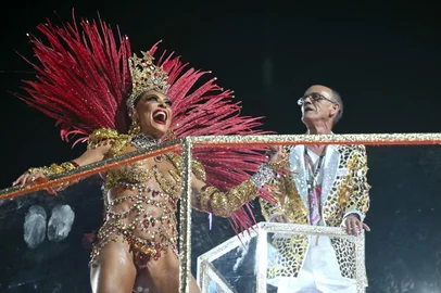 Brazilian drum master Mestre Cica (R) gestures next to a reveller during the parade of the Unidos do Viradouro samba school in his honor on the second night of the Rio Carnival at the Marques de Sapucai Sambadrome in Rio de Janeiro, Brazil, early on February 17, 2026. (Photo by Mauro PIMENTEL / AFP)<!-- NICAID(16227789) -->