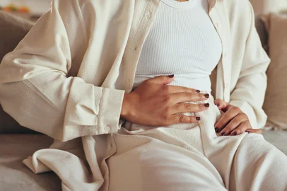 Woman, hands and stomach pain of menstruation on sofa with period cramps, bloating or pms in home. Person, abdomen and endometriosis with constipation, nausea and digestion problem on couch in loungeWoman, hands and stomach pain of menstruation on sofa with period cramps, bloating or pms in home. Person, abdomen and endometriosis with constipation, nausea and digestion problem on couch in lounge. Foto: LuxeShutter24/peopleimages.com/ stock.adobe.comIndexador: Yuri Arcurs peopleimages.comFonte: 983810040<!-- NICAID(16382957) -->