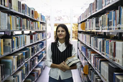 Novo Hamburgo, RS, Brasil, 19-02-2025: A estudante Ágatha Blanco, 23, posa na biblioteca da Feevale, em Novo Hamburgo. A jovem faz licenciatura em História e foi contemplada pelo programa Professor do Amanhã. Reportagem sobre o impacto de programas de incentivo à formação de professores, como o Pé de Meia Licenciaturas e o Professor do Amanhã. Foto: Mateus Bruxel / Agência RBSIndexador: MATEUS BRUXEL<!-- NICAID(15979719) -->