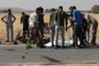 Passersby and gunmen gather around a body at the site of a reported drone strike in Bzaah town near al-Bab in Syria's Aleppo governorate on July 7, 2023. A US drone strike has killed an Islamic State group leader in Syria after Russian warplanes harassed MQ-9 drones over the war-torn country, the US Central Command said on July 9. (Photo by Bakr ALKASEM / AFP)<!-- NICAID(15477815) -->