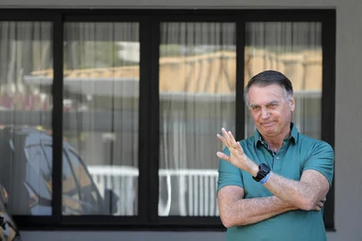 Former Brazilian President Jair Bolsonaro waves at his residence in Brasilia on September 11, 2025. A Brazilian judge on September 10 returned the first not-guilty vote in the coup-plotting trial of former president Jair Bolsonaro, shifting all eyes on the last two of his colleagues left to vote following two guilty findings. The 70-year-old far-right ex-leader risks a prison sentence of more than 40 years if found guilty of seeking to claw back power after his defeat in 2022 elections to leftist Luiz Inacio Lula da Silva (Photo by Sergio Lima / AFP)<!-- NICAID(16122041) -->