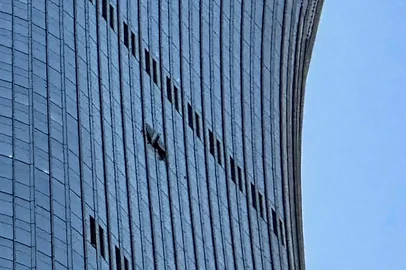 A hole is seen (R) on the side of the CITIC Tower in Beijing on June 26, 2026, after an eyewitness reported plane debris at the base of Beijing's tallest building. Video footage taken from a nearby building by the witness showed fire trucks blasting water at smoke billowing from the 528-metre (1,732-foot) CITIC Tower, while the wreck of a plane lay on the ground beside the building. (Photo by Peter CATTERALL / AFP)<!-- NICAID(16315567) -->