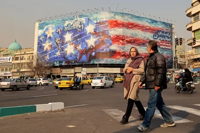 Commuters walk past an anti-US billboard installed on a building at the Enqelab Square in Tehran on January 26, 2026. (Photo by ATTA KENARE / AFP)<!-- NICAID(16213943) -->