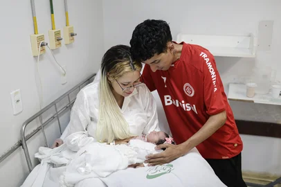PORTO ALEGRE, RS, BRASIL, 01-01-2026: Sofia Maitê repousa nos braços da mãe, a estudante Yasmin Vargas da Silveira, 20 anos, e sob o olhar do pai, o garçom Leonardo Quines Duarte, 23, na maternidade do Hospital Nossa Senhora da Conceição, no bairro Cristo Redentor, zona norte de Porto Alegre. A menina, que nasceu às 0h38min do dia 01 de janeiro, foi o primeiro bebê da capital em 2026. Foto: Mateus Bruxel/Agência RBSIndexador: MATEUS BRUXEL<!-- NICAID(16196446) -->