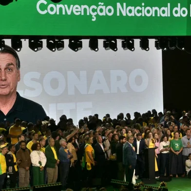 An AI generated video of former president Jair Bolsonaro -who was banned from taking part as he is serving house arrest- is screened during the launching of the presidential candidacy of his son, right-wing presidential hopeful Flavio Bolsonaro within the Liberal Party (PL) convention, in Sao Paulo, Brazil on July 25, 2026. Battered by a string of political crises, Flavio Bolsonaro launched his candidacy for Brazil's October presidential election, seeking to follow in the footsteps of his father, Jair Bolsonaro, who is serving house arrest for plotting a coup after losing the election in 2022. (Photo by Nelson ALMEIDA / AFP)<!-- NICAID(16336469) -->