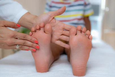 Pediatrician examining development of boyâ€™s feet. Pediatrician examining development boyâs feet on a bed. Indexador: Stevica MrdjaFonte: 459670283<!-- NICAID(16224111) -->