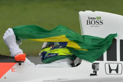 Mercedes' British driver Lewis Hamilton holds a Brazilian flag while driving the McLaren MP4-5B with which the late Ayrton Senna won his second Formula 1 world title in 1990 during a lap to mark the 30th anniversary of Senna's death at the San Marino Grand Prix, ahead of the Formula One Sao Paulo Grand Prix at the Jose Carlos Pace racetrack, aka Interlagos, in Sao Paulo, Brazil, on November 3, 2024. (Photo by NELSON ALMEIDA / AFP)<!-- NICAID(15905868) -->