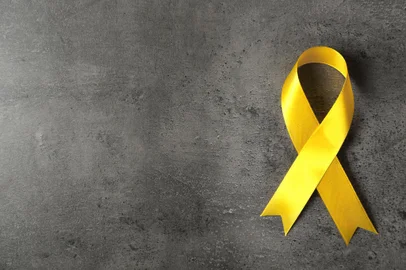 Yellow awareness ribbon on grey textured backgroundFonte: 112641474<!-- NICAID(14877443) -->
