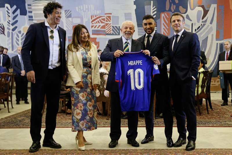 (L-R) Brazilian former football player Rai Souza, Brazil's First Lady Rosangela "Janja" da Silva, Brazil's President Luiz Inacio Lula da Silva, French football player Dimitri Payet and France's President Emmanuel Macron pose for a picture while holding Kylian Mbappe's French national football team jersey at the Itamaraty Palace in Brasilia, on March 28, 2024. (Photo by Ludovic MARIN / POOL / AFP)Editoria: POLLocal: BrasíliaIndexador: LUDOVIC MARINSecao: diplomacyFonte: POOLFotógrafo: STF<!-- NICAID(15719466) -->