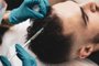 Close-up.Young man receiving hair treatment in a beauty salon. Man having mesotherapy session in aesthetic clinic, therapist hands in gloves making scalp injection.Fonte: 550253619<!-- NICAID(15485587) -->