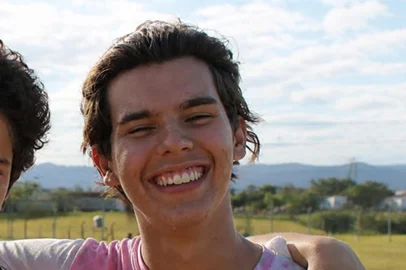 Arquivo pessoal / Arquivo pessoal Daniel Thiesen Pinheiro (à direita, de rosa) foi morto em assalto em estação do trensurb, em Canoas. Na foto, feita com uso de IA pela mãe, ele está ao lado de São Carlo Acutti, do qual era devoto.<!-- NICAID(16280612) -->
