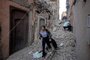 A woman evacuates with her belongings through the rubble in the earthquake-damaged old city of Marrakesh on September 9, 2023. A powerful earthquake that shook Morocco late September 8 killed more than 600 people, interior ministry figures showed, sending terrified residents fleeing their homes in the middle of the night. (Photo by FADEL SENNA / AFP)<!-- NICAID(15536086) -->