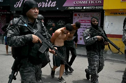 Police officers escort suspects arrested during the Operacao Contencao (Operation Containment) out of the Vila Cruzeiro favela, in the Penha complex, in Rio de Janeiro, Brazil, on October 28, 2025. At least 2,500 agents took part in an operation to arrest drug traffickers from the Comando Vermelho (CV), which resulted in, at least, 18 suspects and several police officers dead. (Photo by Mauro PIMENTEL / AFP)Editoria: CLJLocal: Rio de JaneiroIndexador: MAURO PIMENTELSecao: security measuresFonte: AFPFotógrafo: STF<!-- NICAID(16155748) -->