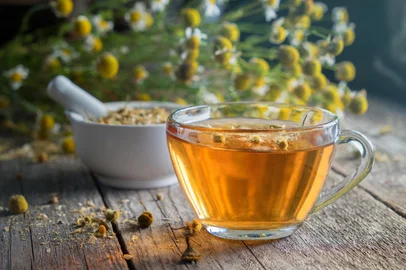 Healthy chamomile tea or infusion, mortar and daisy herbs on wooden table.Fonte: 213647339<!-- NICAID(15537063) -->
