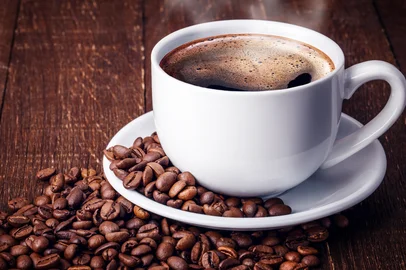 Xícara de café preto. Grãos de café ao redor<!-- NICAID(15186177) -->