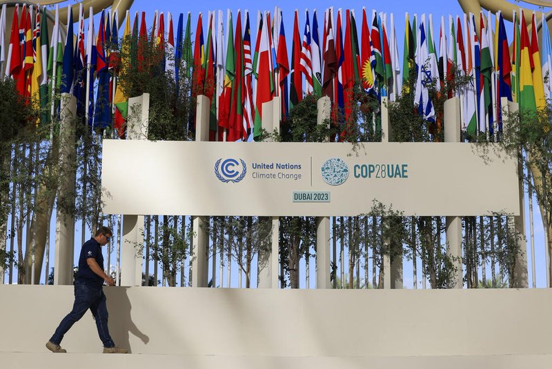 A man walks past national flags of participating countries at the venue of the COP28 United Nations climate summit in Dubai on November 30, 2023. The UN climate conference opens in Dubai on November 30 with nations under pressure to increase the urgency of action on global warming and wean off fossil fuels, amid intense scrutiny of oil-rich hosts UAE. (Photo by Karim SAHIB / AFP)Editoria: WEALocal: DubaiIndexador: KARIM SAHIBSecao: diplomacyFonte: AFPFotógrafo: STF<!-- NICAID(15612677) -->