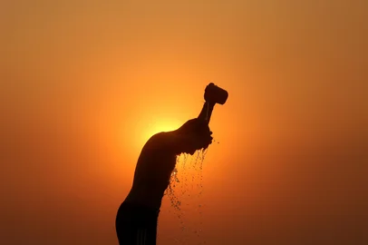Mukesh GUPTA / AFP (FILES) A labourer is silhouetted against the setting sun as he bathes on a hot summer day in Jammu on June 1, 2024. Temperatures passed 50 degrees Celsius (122 Fahrenheit) in northern India as an unrelenting heatwave triggered warnings of water shortages and heatstroke. 2024 is confirmed by the Copernicus Climate Change Service (C3S) to be the warmest year on record globally, and the first calendar year that the average global temperature exceeded 1.5°C above its pre-industrial level. C3S is implemented on behalf of the European Commission by the European Centre for Medium-Range Weather Forecasts (ECMWF), whose scientists have been monitoring key climate indicators, and documenting unprecedented daily, monthly, and annual temperature records over 2024. (Photo by Mukesh GUPTA / AFP)Editoria: WEALocal: JammuIndexador: MUKESH GUPTASecao: reportFonte: AFPFotógrafo: STR<!-- NICAID(15970530) -->