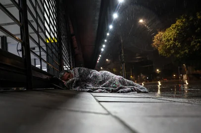 Porto Alegre, RS, Brasil - Na capital, moradores em situação de rua buscam abrigo sob a marquise de uma loja na Avenida Ipiranga, junto à Excelsior, para se proteger da chuva e do frio que marcaram os últimos dias na capital. Sem acesso a estruturas adequadas, recorrem a cobertores, lonas e improvisos enquanto a cidade enfrenta mais uma onda de baixas temperaturas."<!-- NICAID(16061399) -->