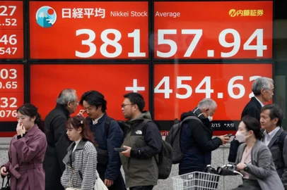 Pedestrians walk past an electronic board showing the closing numbers of the Tokyo Stock Exchange along a street in Tokyo on February 15, 2024. (Photo by Kazuhiro NOGI / AFP)<!-- NICAID(15680231) -->