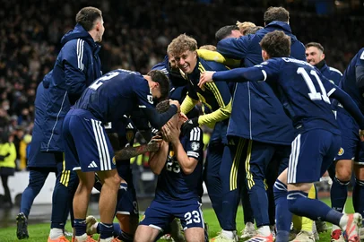ANDY BUCHANAN / AFP Scotland's midfielder #23 Kenny McLean (C) celebrates with teammates after scoring his long-range last-kick of the game goal during the FIFA World Cup 2026 European qualification football match between Scotland and Denmark at Hampden Park in Glasgow on November 18, 2025. Scotland scored two dramatic stoppage-time goals to beat 10-man Denmark 4-2 on Tuesday and reach the World Cup for the first time since 1998. (Photo by ANDY BUCHANAN / AFP)<!-- NICAID(16169977) -->
