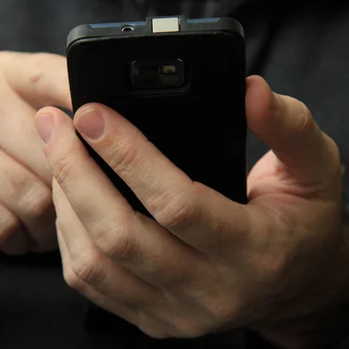 Homem mexendo em seu celular do tipo smartphone.<!-- NICAID(15278519) -->