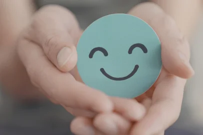Hand holding green happy smile face paper cut, mental health assessment, child positive wellness, world mental health day concept<!-- NICAID(15916134) -->